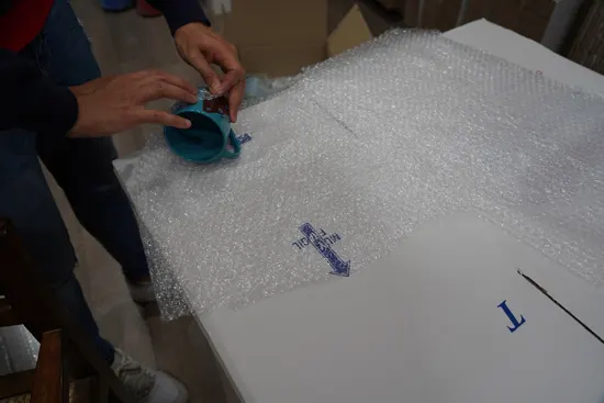 un operario de Transiv realizando servicios  de embalaje de de vajilla en plástico con burbujas.