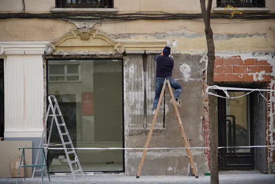 Un operario de Transiv realizando servicios de rehabilitación en la fachada de la tienda de embalajes de Transiv ubicada en Chamberí Madrid